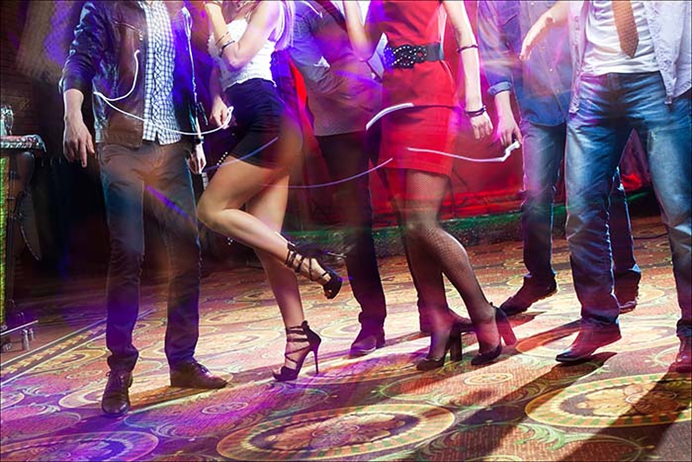 Pieds de danseurs sur une piste de danse éclairée